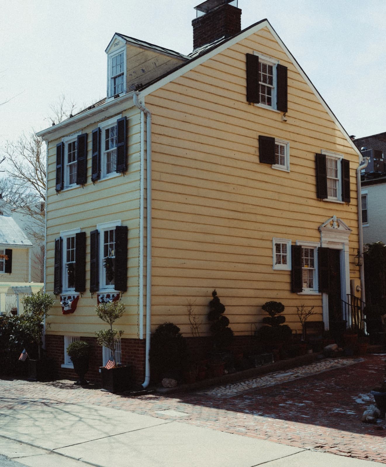 Yellow clapboard house with black shutters